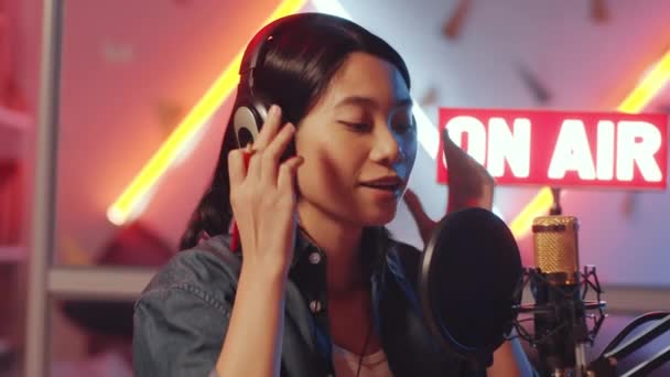 Genç Asyalı Kadın Radyo Sunucusunu Kulaklıkları Takarken Mikrofona Konuşurken Stüdyoda — Stok video