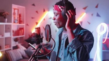 Genç Afro-Amerikalı bir adamın kulaklıkla akıllı telefon ekranına bakarken ve mikrofondan rap okurken Asyalı bir kadın müzisyenin masa başında konsol ve dizüstü bilgisayarla müzik kaydettiği görüntüleri.
