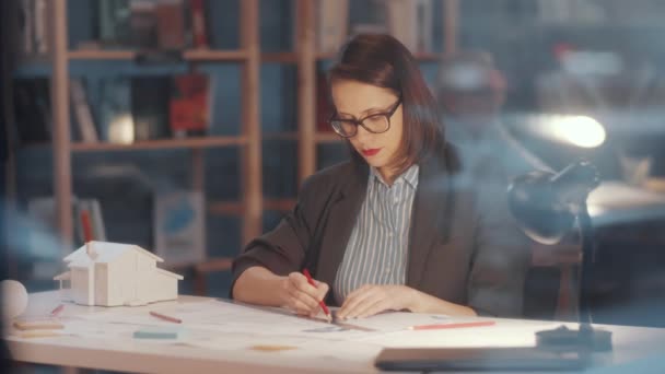 Вид Сквозь Стеклянную Стену Профессиональной Женщины Архитектора Рисует План Строительства — стоковое видео