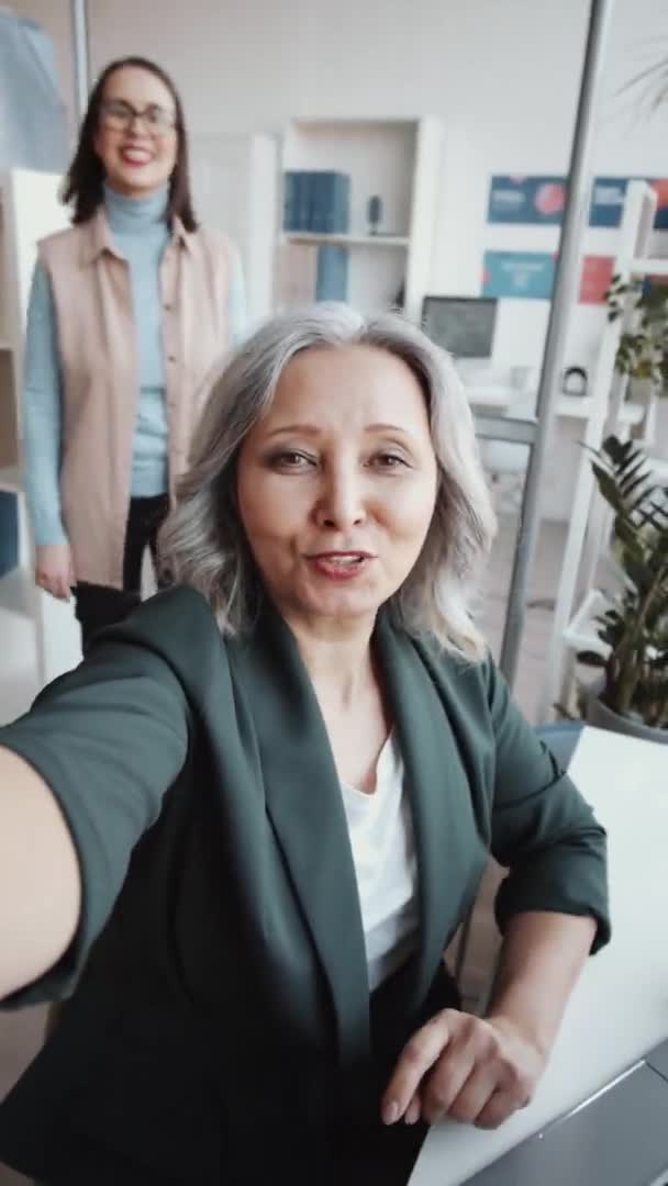 在办公室里一起工作时 男女同事面带微笑 对着相机挥手 并在网上视频通话中进行垂直拍照 — 图库视频影像