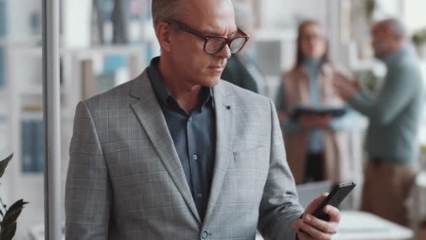 사업가가 사무실에서 스마트폰으로 타이핑하고 카메라를 모습을 선택적으로 — 비디오