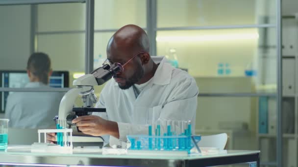 Tracking Shot African American Scientist White Coat Sitting Desk Laboratory — Vídeos de Stock