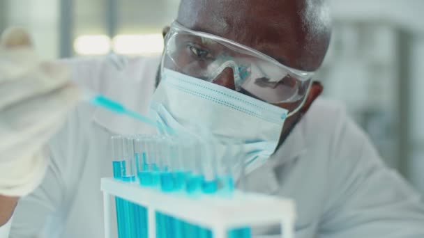 Afroamerykanin Naukowiec Masce Ochronnej Okularach Rękawiczkach Wlewający Niebieski Płyn Probówek — Wideo stockowe