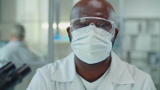 보호용 마스크와 안경을 아프리카 미국인 과학자 실험실에서 카메라에 포즈를 취하는 — 비디오