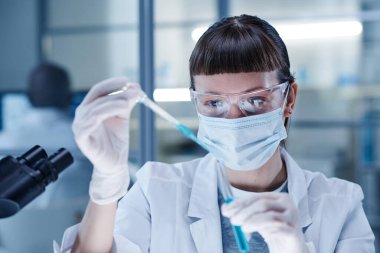 Maskeli kadın örneği inceliyor.