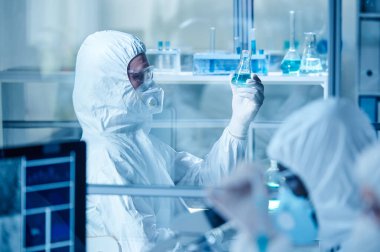 Laboratuvar teknisyeni laboratuarda koruyucu giysiyle çalışıyor.