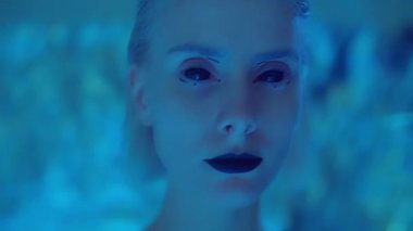 Moda modelinin yakın plan çekimleri, kontakt lensleri ve siyah rujla stüdyoda hareket eden düz lazer ışığı ile kameraya poz veriyor.