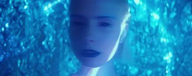 Stüdyo çekimlerinde siyah gözlü ve dudaklı güzel uzaylı kadın kameraya mavi neon ışıkta poz veriyor ve yüzüne lazer ışınları yansıtılıyor.