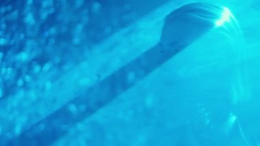 Metalik elbiseler içinde dünya dışı güzel bir kadın karanlık stüdyoda düz bir gökyüzü lazer ışığının içinden geçiyor.