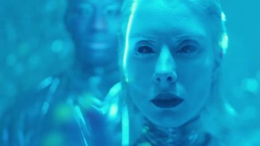 Karanlık dudakları ve karanlık lensleri olan güzel uzaylı kadın portresi mavi neon ışık ve lazer ışınlarıyla dolu bir adamla aynı odada duruyor.