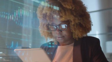 Yatırım şirketinin ofisinde dijital tablet üzerinde çalışan Afrikalı Amerikalı iş kadınlarının cam duvarından bakın.