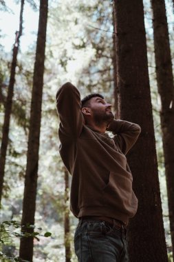 Ormana bakan bir adam. Adam başının arkasında el ele tutuşup Karpatlar 'ın Ukrayna' daki orman bölgesine bakıyor..