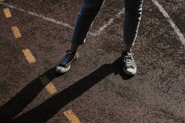 Basketbol sahasında sarı ve beyaz çizgili siyah beyaz spor ayakkabılı bir kız..