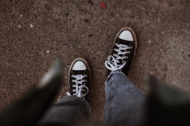 Spor ayakkabılı kadın ayakları günlük kıyafetlerle beton yolda yürüyor..