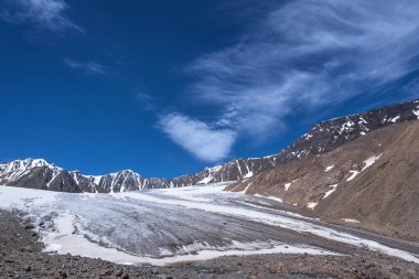 Buzulların, karlı zirvelerin ve dağların üzerinde mavi gökyüzünde güzel pofuduk sirrus bulutlarıyla muhteşem bir yaz manzarası. Altai, Rusya