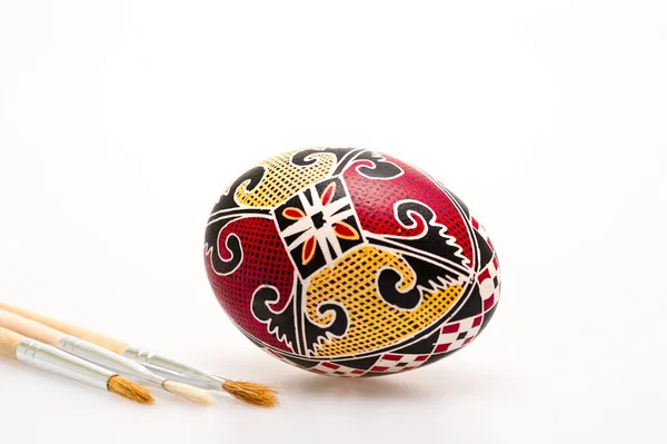 Colorful hand painted Easter egg and paint brushes — Stock Photo, Image