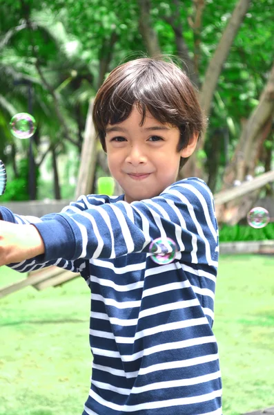 Malý chlapec hraje bubliny v parku — Stock fotografie