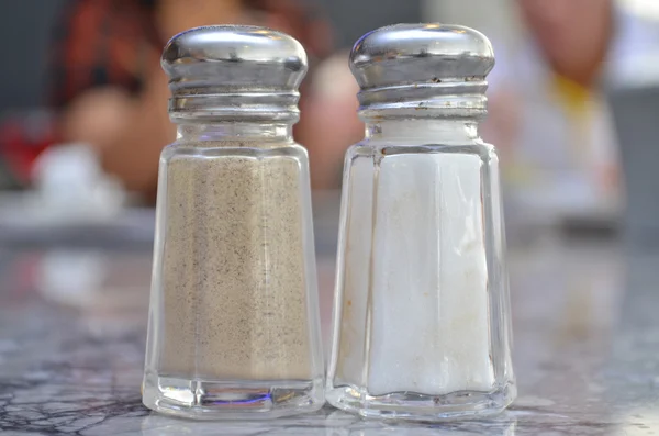 Saleiro de vidro e pimentão shakers na mesa — Fotografia de Stock