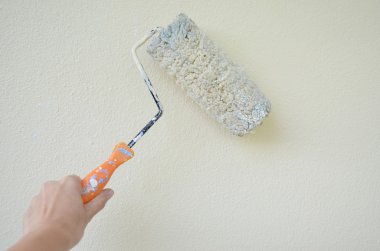 kadın el boya silindiri ile beyaz bir duvar boyama