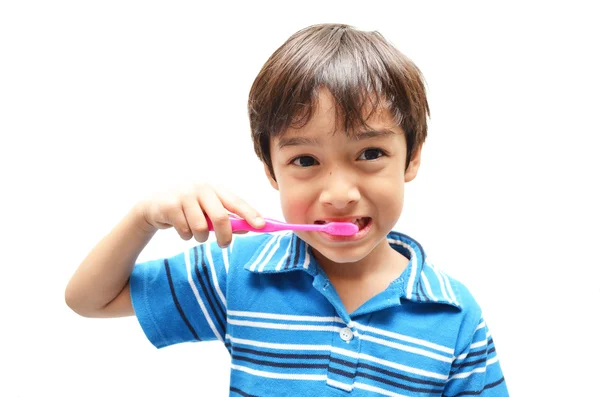 Маленький мальчик чистит зубы на белом фоне — стоковое фото