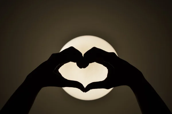 Coeur forme femme main fabrication sur la lumière Silhouette — Photo