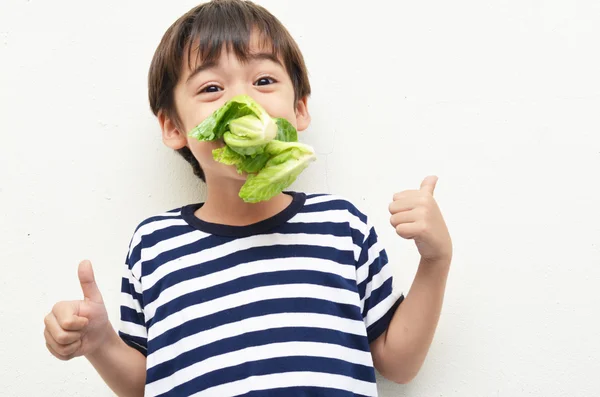 Маленький хлопчик їсть зелений овоч для здоров'я смішне обличчя — стокове фото
