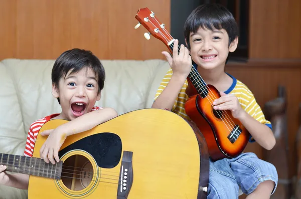 Little sibling boy playing guitar and ukulele happy face — Stock Photo, Image