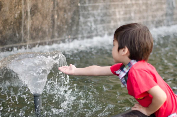 水噴水に触れる小さな男の子 — ストック写真