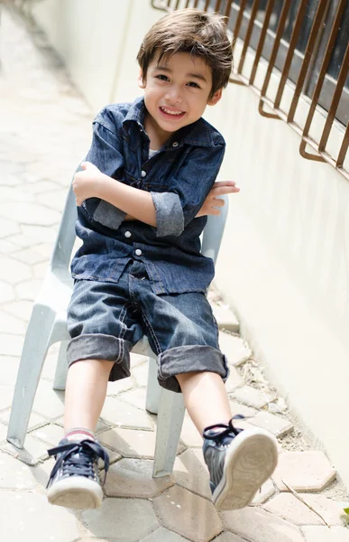 Petit garçon assis sur une chaise portrait avec sourire en plein air — Photo