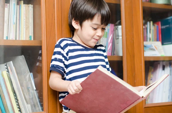 Хлопчик у бібліотеці тримає книгу — стокове фото