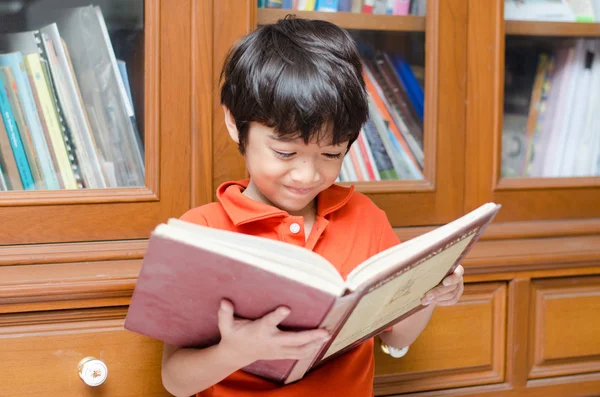 Kleiner Junge in Bibliothek hält Buch — Stockfoto