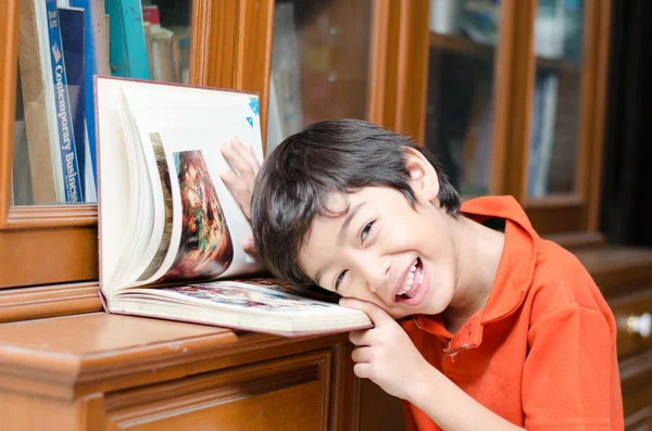 Pequeño hermano en biblioteca sosteniendo libro — Foto de Stock