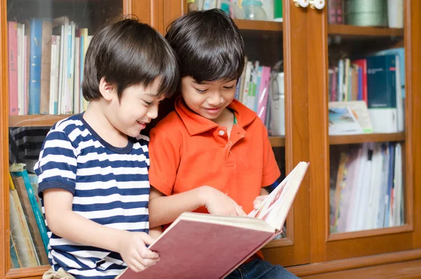 Pequeño hermano en biblioteca sosteniendo libro — Foto de Stock