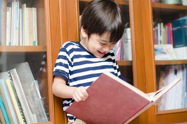 Маленький хлопчик у бібліотеці тримає книгу — стокове фото