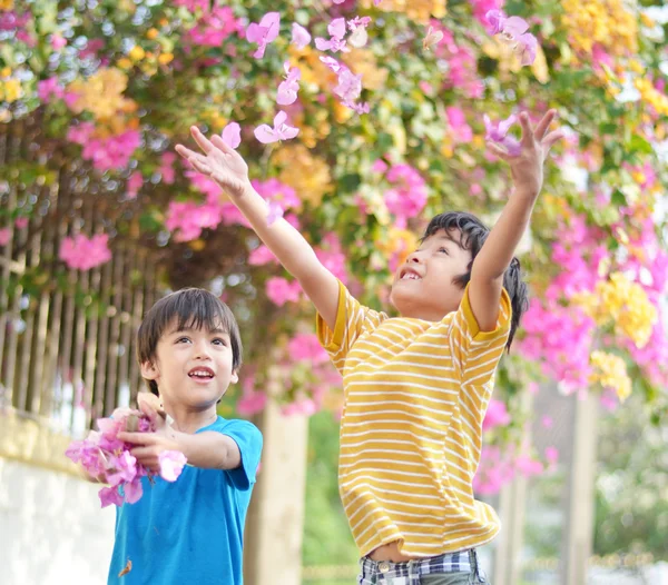 Lilla syskon pojke kasta blommor i luften — Stockfoto