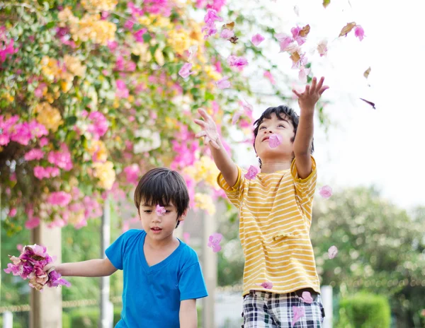 Little sibling boy throw flowers in to the air — Stock Photo, Image