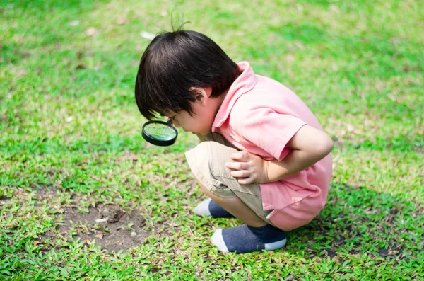 Little boy exploring with magnifying glass at the park — Stock Photo, Image