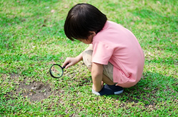 Kleine jongen verkennen met vergrootglas in het park — Stockfoto