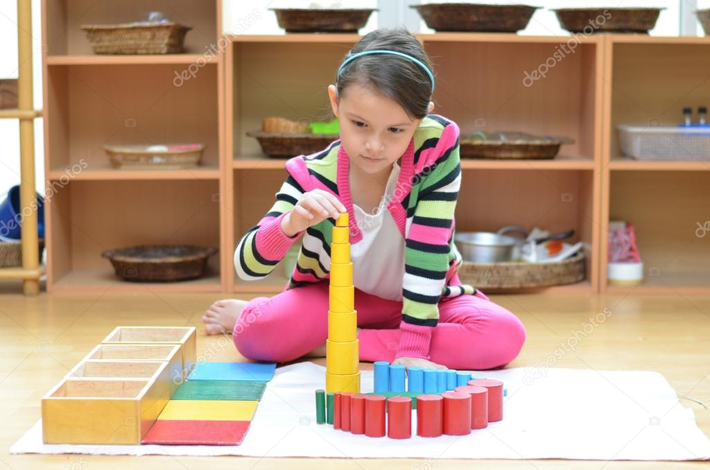 Little girl hand building tower made of montessori educational m