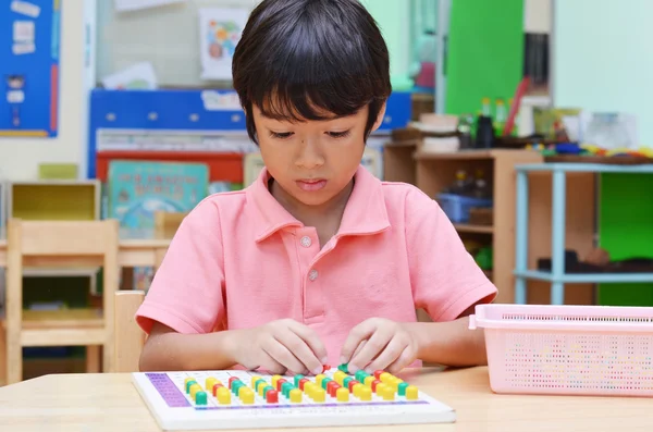 Malého chlapce studovat barva PIN z montessori vzdělávací mat — Stock fotografie