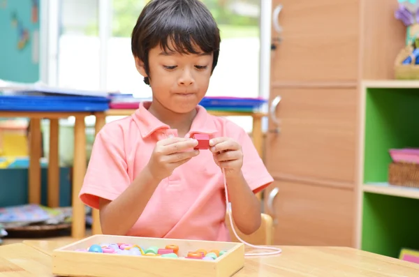 Niño pequeño con cuentas de material Montessori de color — Foto de Stock