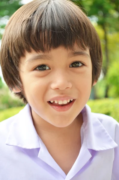 Ładny chłopczyk uśmiechając się w ogrodzie — Zdjęcie stockowe