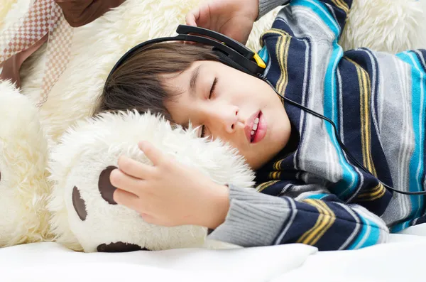 Liten pojke lyssna på musik med headsetet när du sover — Stockfoto