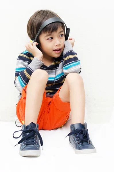 Niño escuchando la música con auriculares —  Fotos de Stock