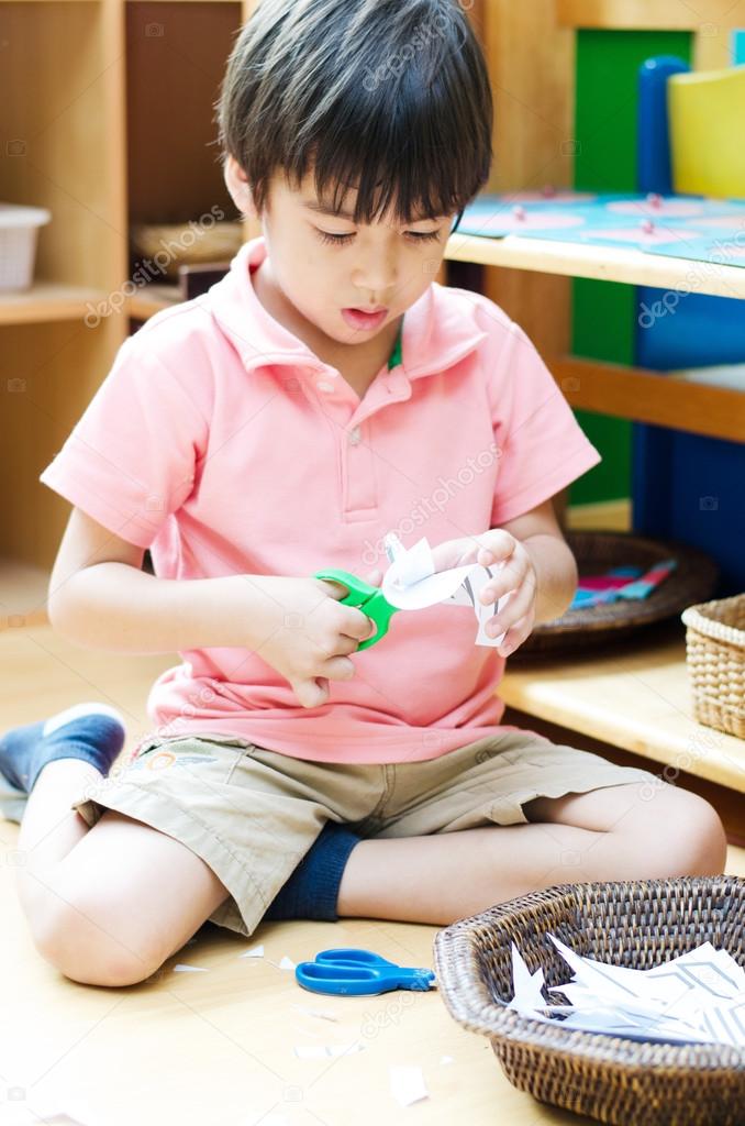 Little boy cutting paper of montessori educational 