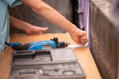 Genç oğlan tornavida kullanıyor, tahta masayı tamir ediyor.