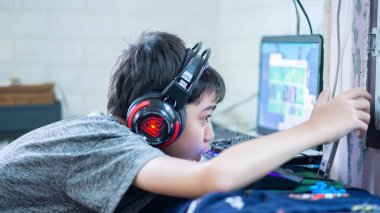 Gençlik kulaklıkla bilgisayar oyunu oynuyor