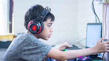 Gençlik kulaklıkla bilgisayar oyunu oynuyor