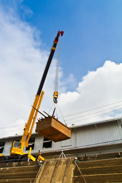 Yellow mobile crane hydraulic boom raises tray over dry dock — Stock Photo, Image