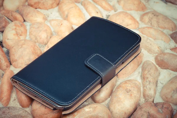 Housse de protection en cuir pour smartphone sur sol en gravier dans un style vintage — Photo